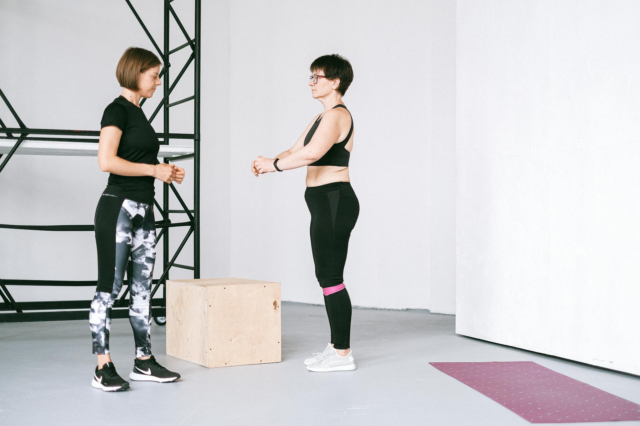 Two women exercising indoors, focusing on fitness and healthy lifestyle with guidance.